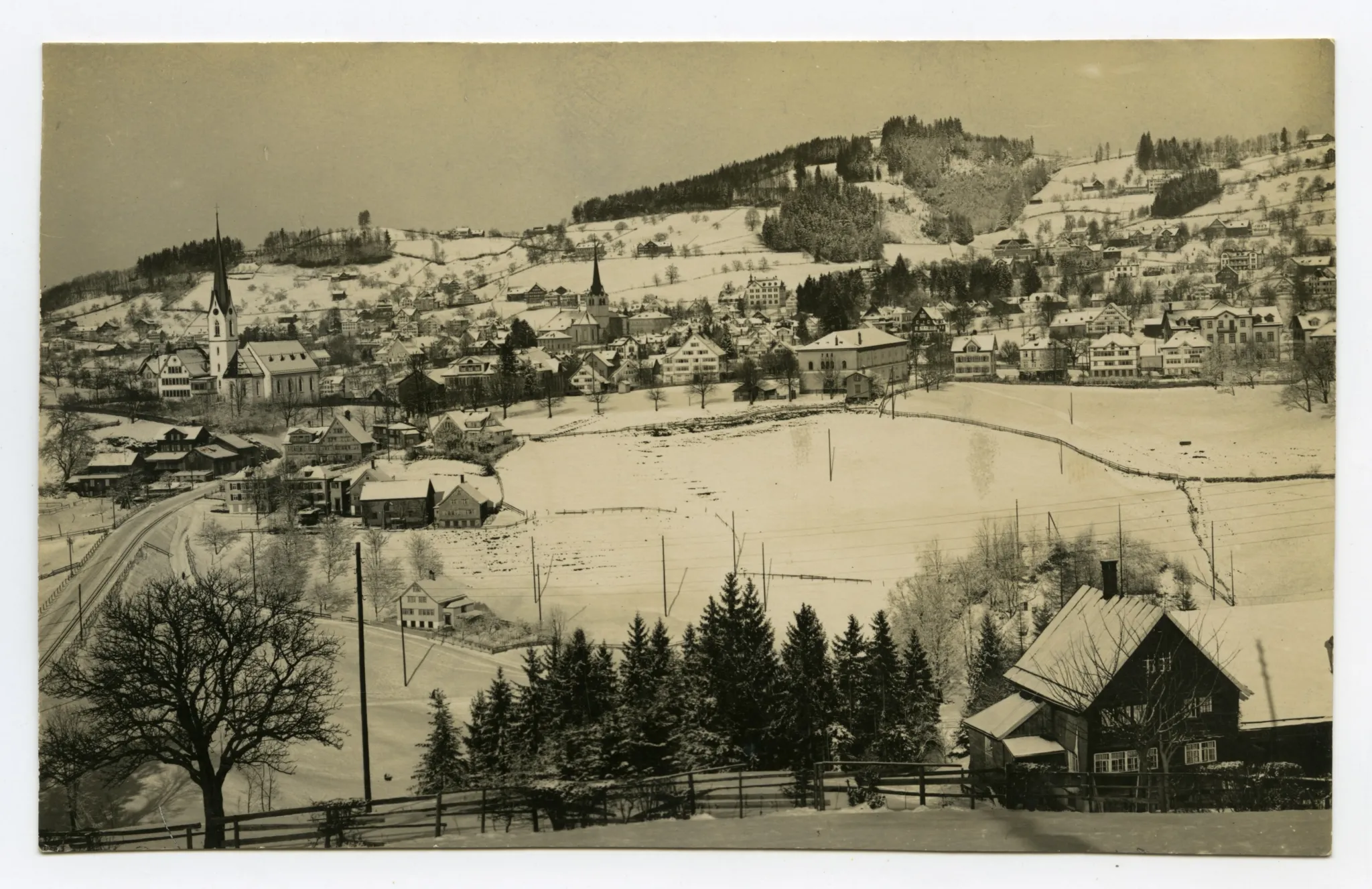 von Schlatterlehn/Bruggtobel?). Vorne Sammelbüel, alte Kath. Kirche, mit Zeughaus, Bahnhof, Krankenhaus, Dorfzentrum, Fernblick, Bad Sonder. Blick zu Schwendibüel, Frölichsegg
