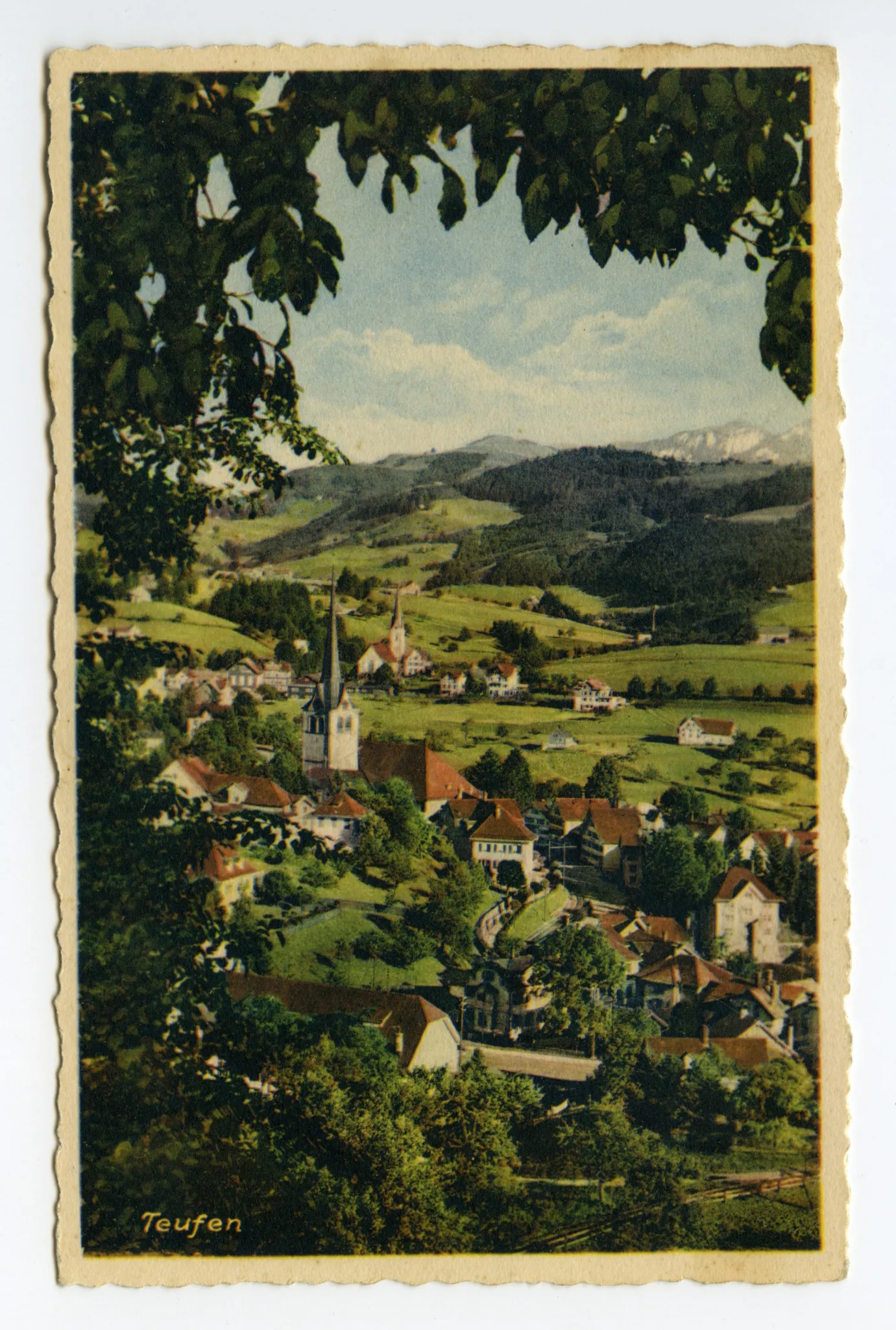 (mit Laub „umrahmt“), vorne alte Turnhalle (halb verdeckt), beide Dorfkirchen. Blick zu Steigbach (Hochkamin), Fänern, Kamor, Hohem Kasten (z.T.)