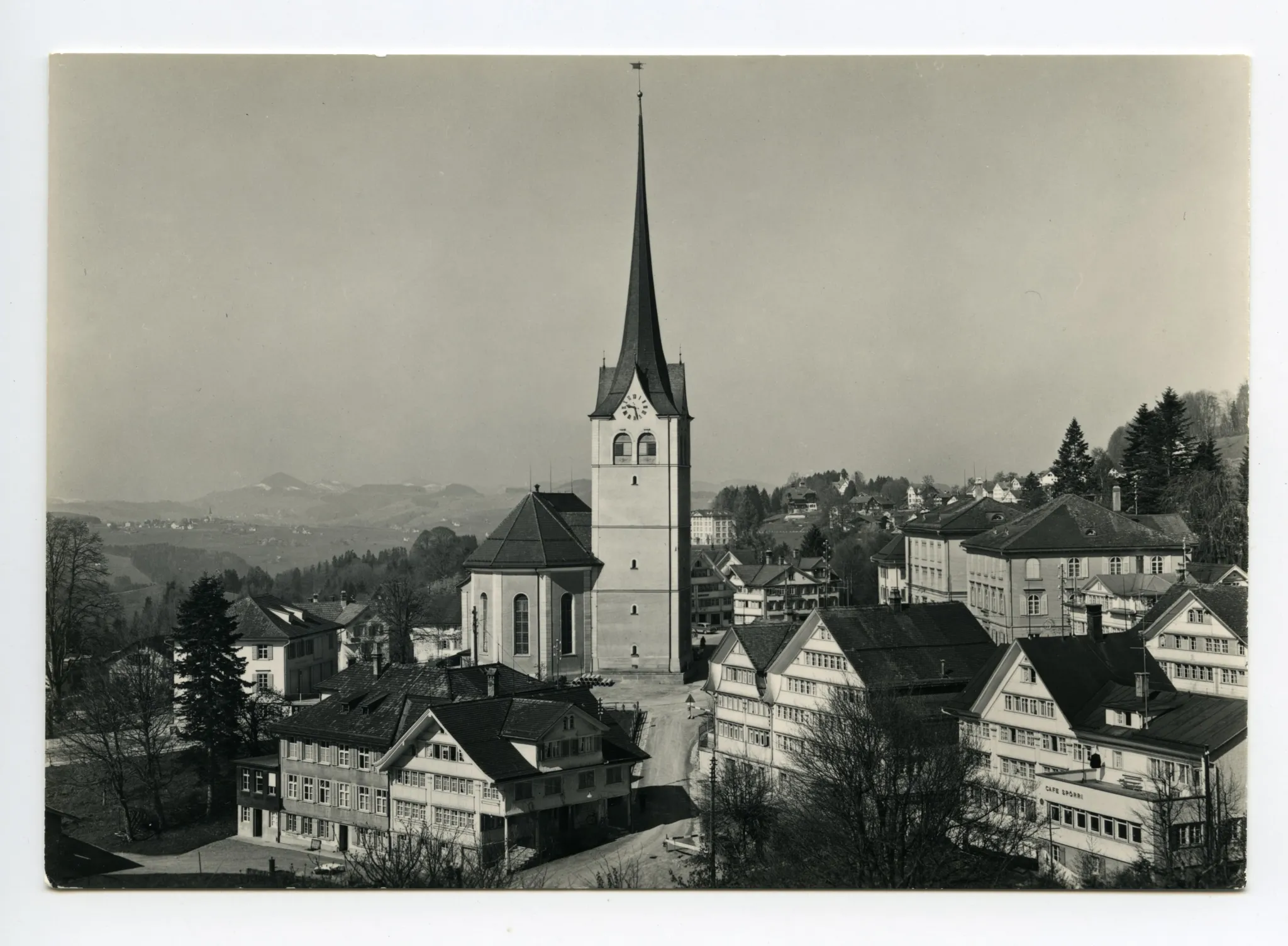 (Querformat), „Hecht“, „Spörri“, Kornhändlerhaus, Dorfplatz mit Grubenmannkirche, Blick Richtung Westen (vgl. Ho.07-092, fast identisches Foto, Autos, Kirchenuhr!)