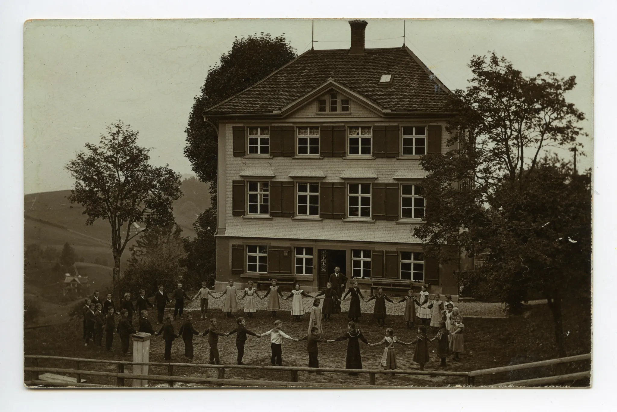 mit Schülern und Schülerinnen im grösseren Kreis, Lehrer dahinter stehend
