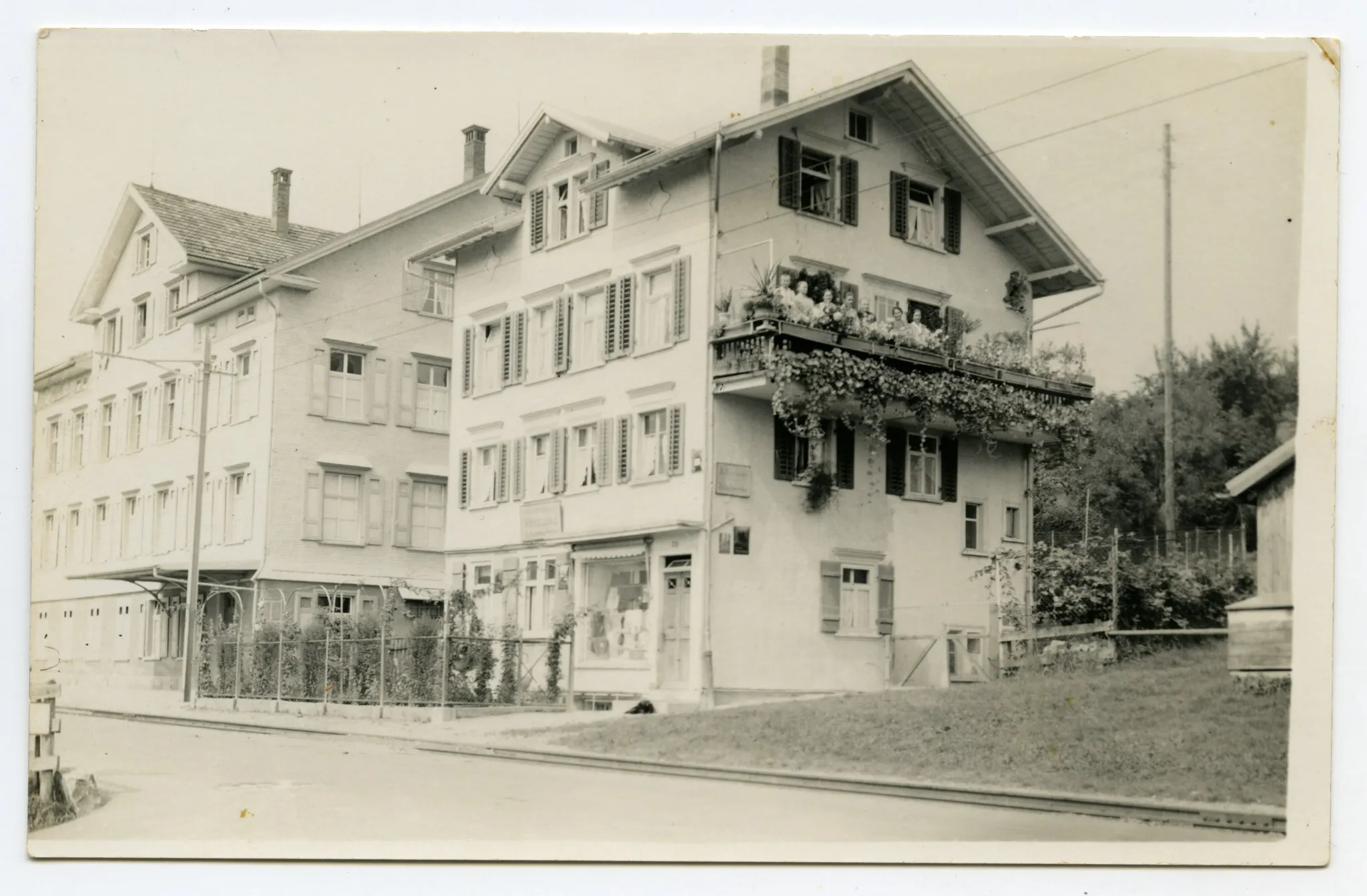 Gebäudeansicht mit Personen auf dem Balkon, angrenzend Fabrikgebäude „Gebrüder Tobler & Cie.“