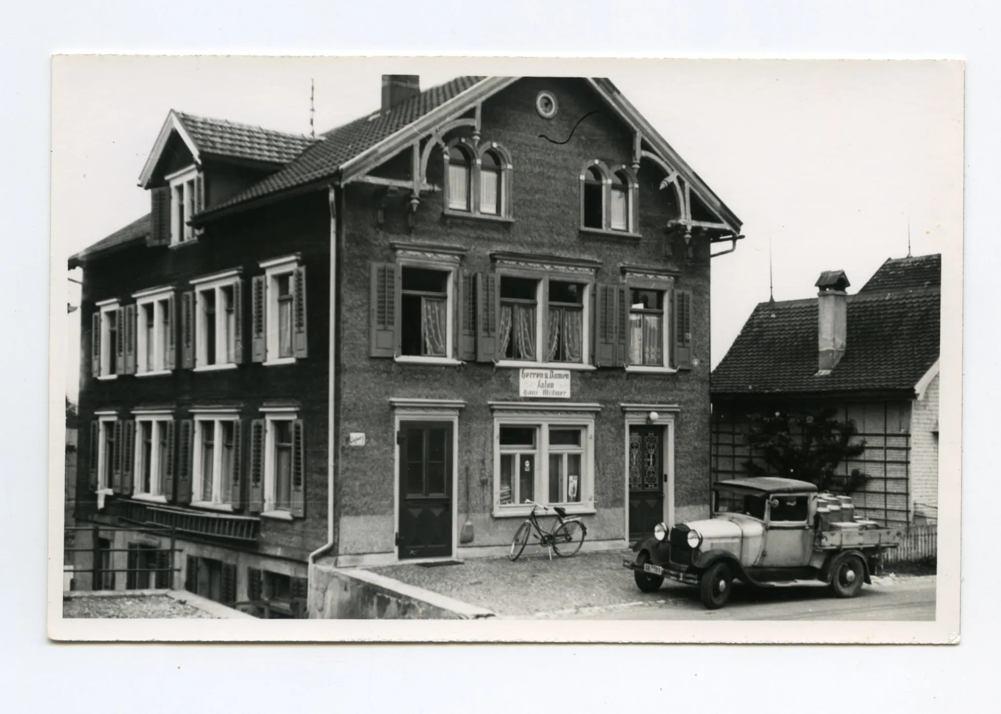 Gebäudeansicht mit Velo und Milchwagen vor dem Haus, Karten identisch