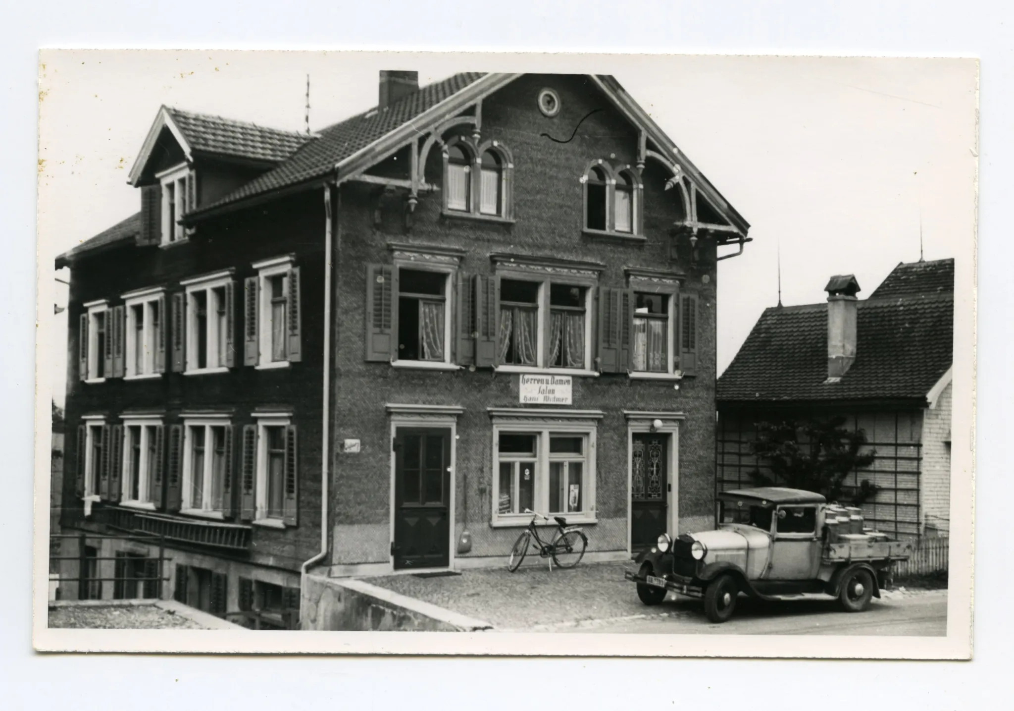 Gebäudeansicht mit Velo und Milchwagen vor dem Haus, Karten identisch