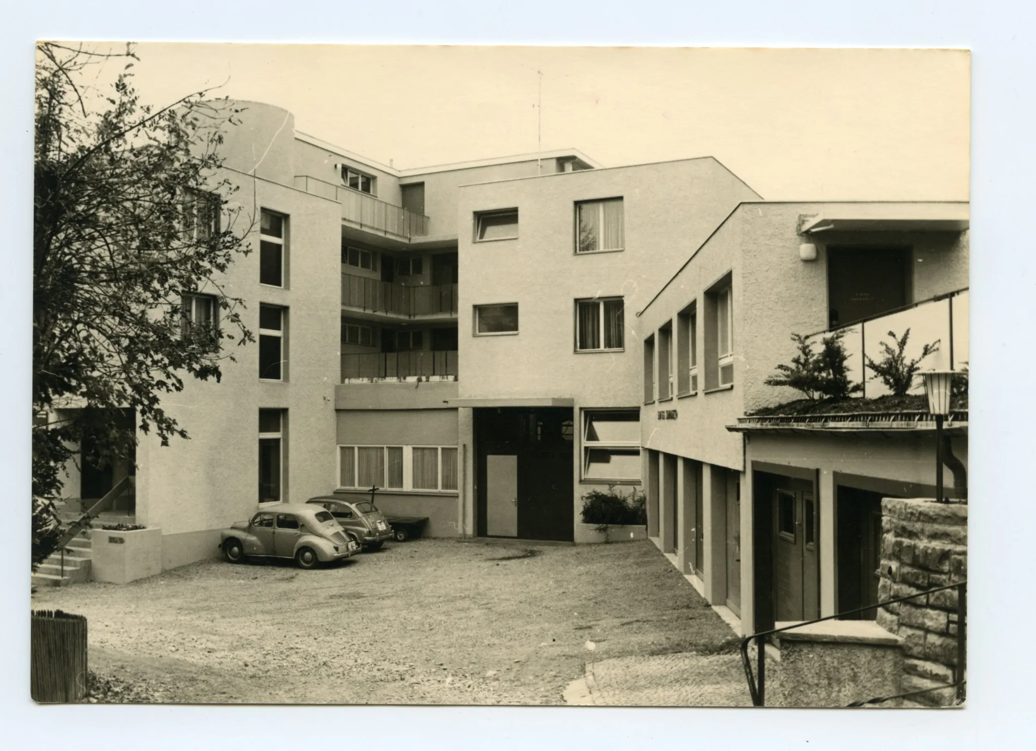 Karte 1: Firmenkomplex mit Eingangsbereich und parkenden Autos; Karte 2: Rückansicht des Firmengebäudes (Mietwohnungen mit Balkon)