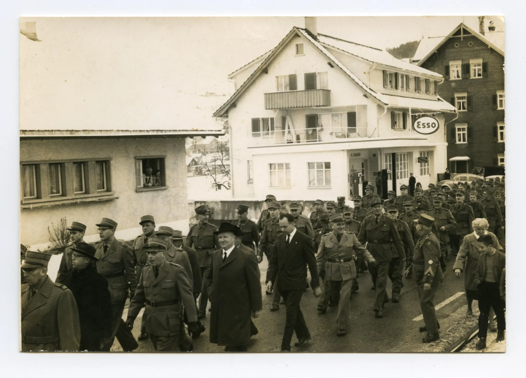 Wehrmänner marschieren auf der Strasse (Ebni) Richtung Zeughaus, Im Hintergrund Tankstelle