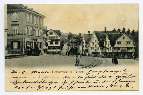 mit Gemeindehaus, „Adler“, Kornhändlerhaus, Dorfstrasse. Im Vordergrund Menschen auf der Strasse, Bahn-Weiche vor Gde-Haus