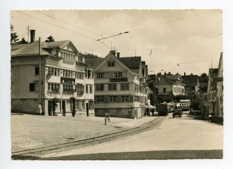 mit „Anker“ und „Adler“, Blick zur Dorfstrasse-Ost und Villa Roth. Elektro-Komposition der SGA, Fahrt Richtung Gais, Autos. Vor Kornhändlerhaus (z.T. sichtbar) Wegweiser: Prof. Buser: „Töchterinstitut mit Kinderhaus“