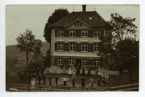 mit Schülern und Schülerinnen im grösseren Kreis, Lehrer dahinter stehend