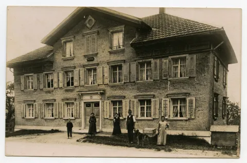 Ansicht mit Hausbewohnern vor dem Haus
