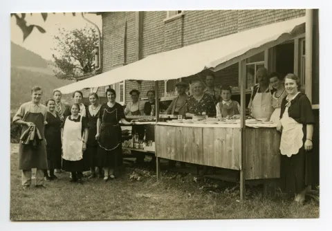 Ansicht der Haus aufgestellten Theke mit Personal (ebenfalls Volksfest?)