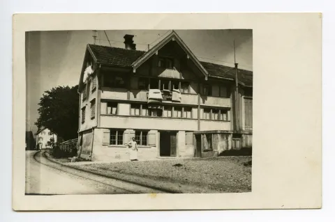 abgebrochen 1977, Ansicht mit Person vor dem Haus und Bahnschienen