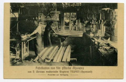 Blick in die Werkstatt mit drei Mitarbeitenden und Holzskimodellen