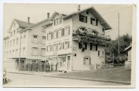 Gebäudeansicht mit Personen auf dem Balkon, angrenzend Fabrikgebäude „Gebrüder Tobler & Cie.“