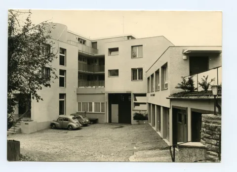Karte 1: Firmenkomplex mit Eingangsbereich und parkenden Autos; Karte 2: Rückansicht des Firmengebäudes (Mietwohnungen mit Balkon)