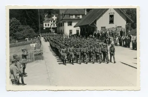 Soldaten (Kompanie) marschieren Richtung Zeughaus, Ebnimit Schaulustigen vor dem Nebengebäude des Bahnhofs, im Hintergrund ehemalige Villa Roth
