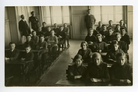 drei Lehrer mit Schülern und Schülerinnen sitzend in den Bänken (vgl. 01-04, gleiche Lehrer, aber andere Schulklasse, dat. 1913)