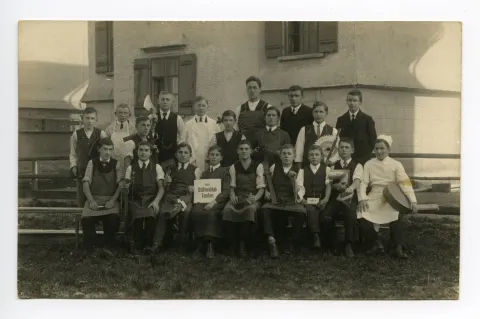 Lehrlinge mit ihren Handwerksutensilien vor dem Schulhaus