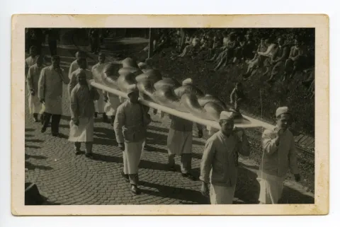 Gruppe der Bäcker, sechs Bäcker tragen einen riesengrossen Zopf