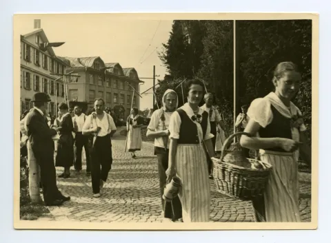 Gruppe der Bauern und Bäuerinnen laufend auf der Hauptstrasse, im Hintergrund: Gebäude Druckerei Kunz, Nahaufnahme