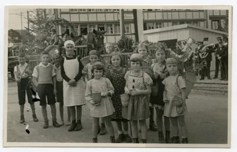 Gruppe von Kindern (Schüler) in Vorbereitung für den Umzug vor dem Restaurant Rössli Niederteufen, Kinder haben Chränzen auf dem Rücken und Beerenkörbe umgebunden