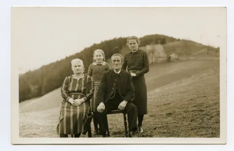 Familienfoto mit Vater, Mutter und zwei Töchtern auf der Wiese