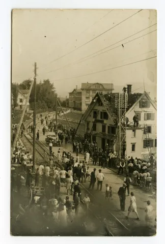 (11. Sept. 1929), Ansicht des Hauses mit Feuerwehrmännern beim Löschen, viele Schaulustige, Bahngleis sichtbar, Blick Richtung Druckerei-Kunz